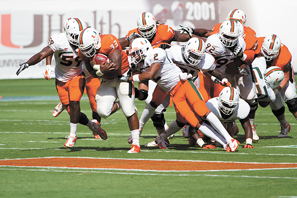 Junior Maurice Hagens (33) clutches the ball as he tries to outrun the white team at  the Spring Football game on Saturday. The orange team won the scrimmage. Nick Gangemi // Staff Photographer