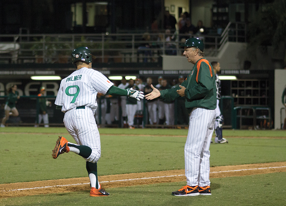 Senior Tyler Palmer celebrates with baseball head coach Jim Morris after hitting a homerun during the first game of the season on Friday night. The Canes won the series against Maine. Monica Herndon // Photo Editor