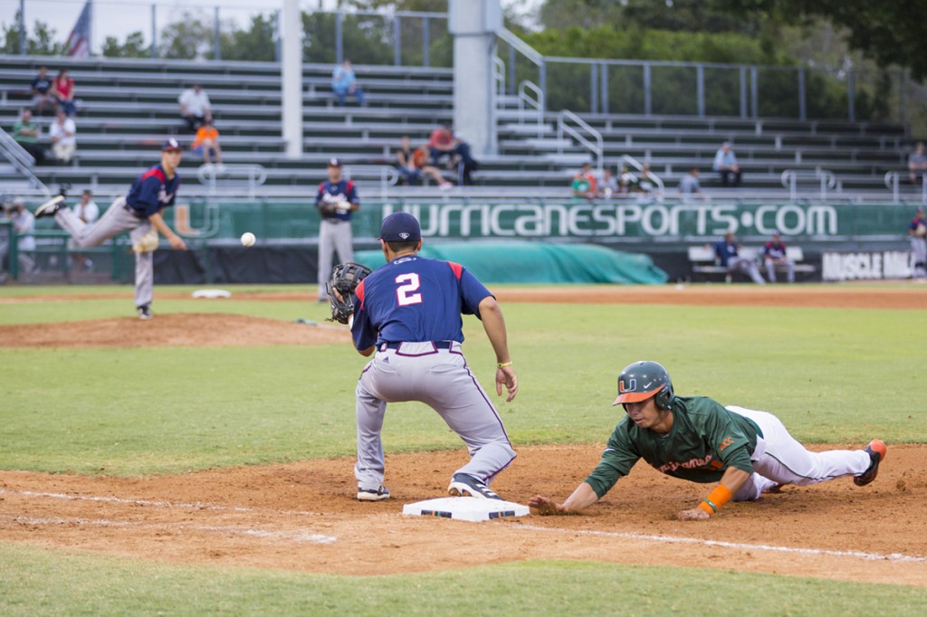 Sophomore Brandon Lopez slides to first as the FAU pitcher makes a pickoff attempt during Wednesday evening’s game.  Nick Gangemi // Assistant Photo Editor
