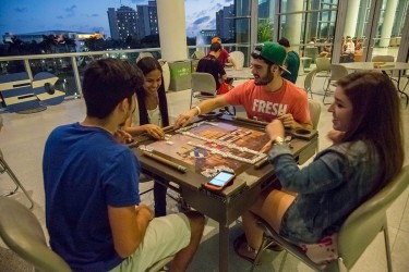 Junior Christian Perez, freshman Patricia Colon, junior Daniel Cantrelle and freshman Ashley Bahamonde (left to right) play a game of dominos on the Moss Terrace as part of  Week of Cuban Culture.