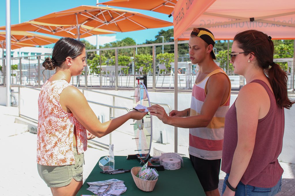 Senior Student Government Senator Robert Renfro gives junior Olivia Gassner a raffle ticket at the “Get To Know Your Senators" event, hosted as part of Student Government Awareness Week, Wednesday afternoon on the Lakeside Patio. Hallee Meltzer // Photo Editor
