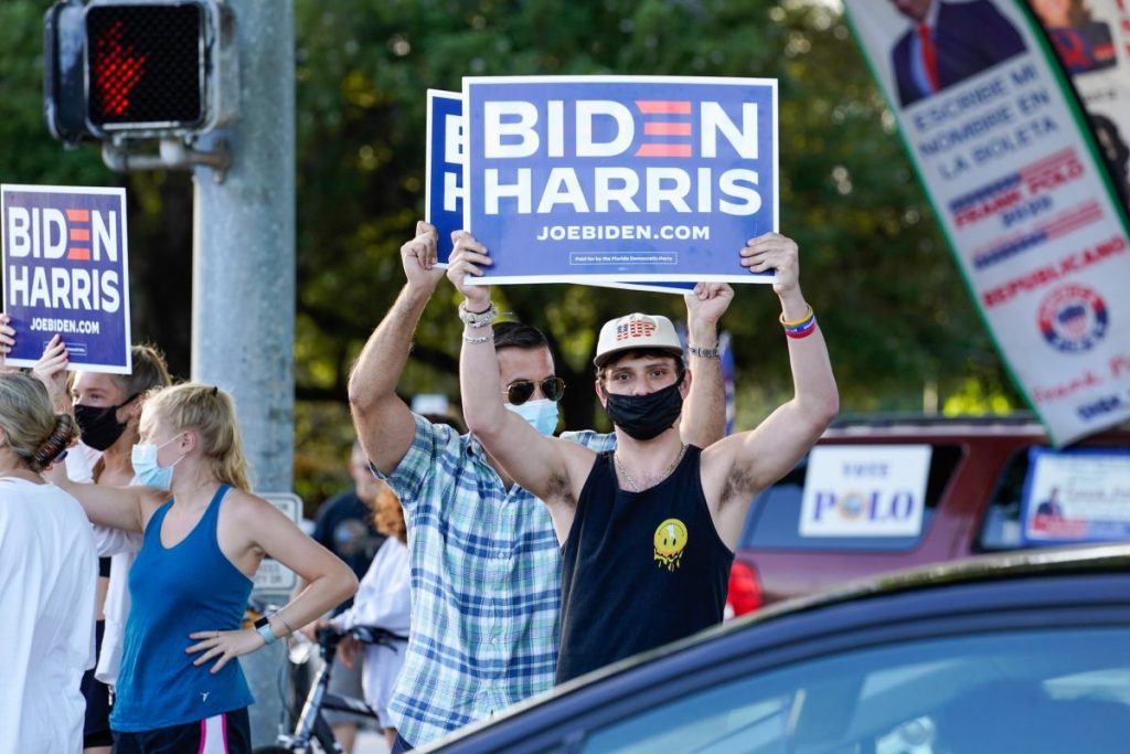 Biden supporters hold campaign signs at an intersection near the Coral Gables Library on Tuesday, Nov. 3.