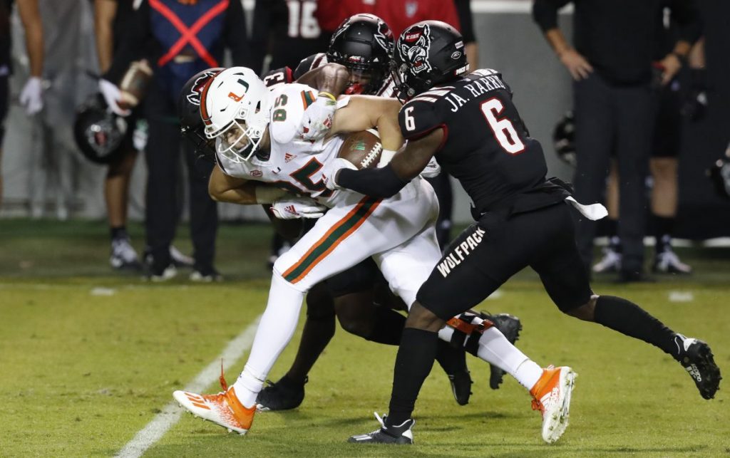 Miami tight end Will Mallory (85) is tackled by N.C. State safety Jakeen Harris (6), Tyler Baker-Williams (13) and Cecil Powell (4) during the first half of Miami's game versus N.C. State at Carter-Finley Stadium in Raleigh, North Carolina on Friday, Nov. 6.
