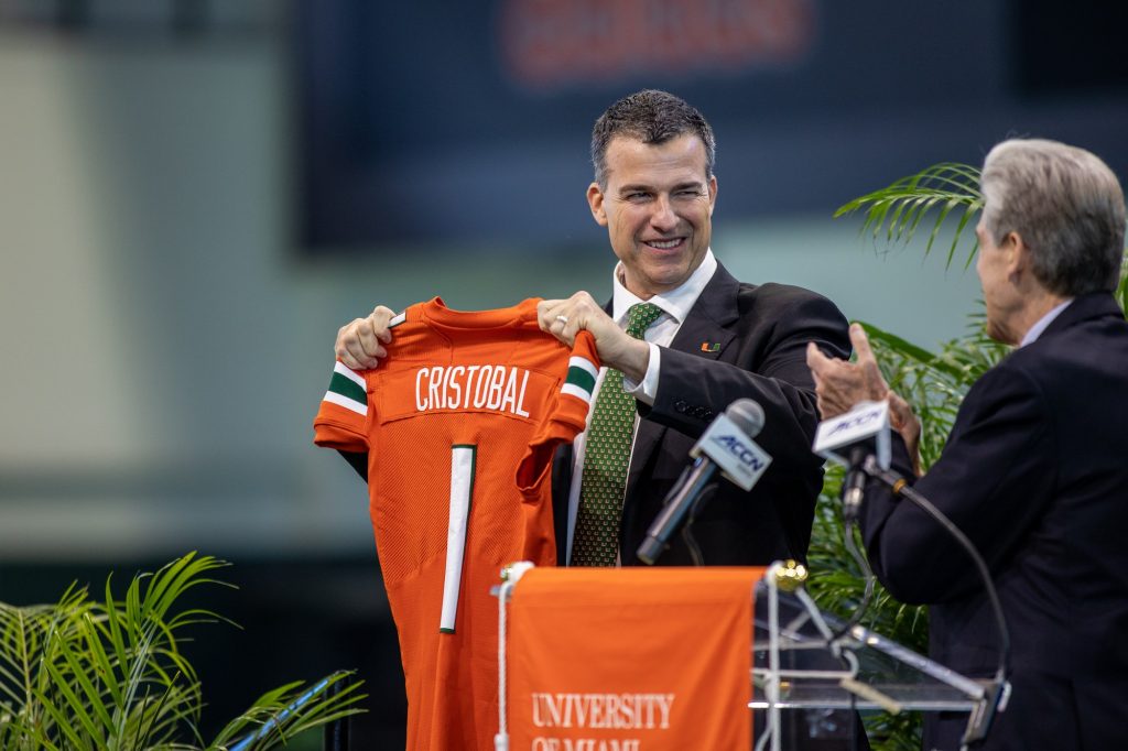 Head coach Mario Cristobal holds up a Miami jersey as he is introduced by University President Julio Frenk at the Carol Soffer Indoor Practice Facility on Tuesday, Dec. 7.