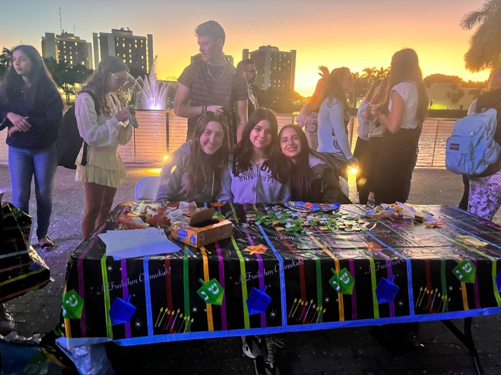 Alex Berman, Rachel Reylder and Hannah Kuker (right to left) give out chocolate coins at Lakeside Patio during the Giant Menorah Lighting on Nov. 30.