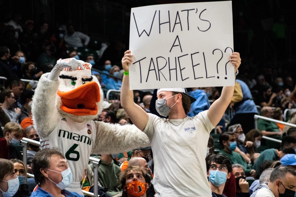 A UM fan holding a sign poses with Sebastian the Ibis during Miami's win over UNC on Jan. 28, 2022 at the Watsco Center.