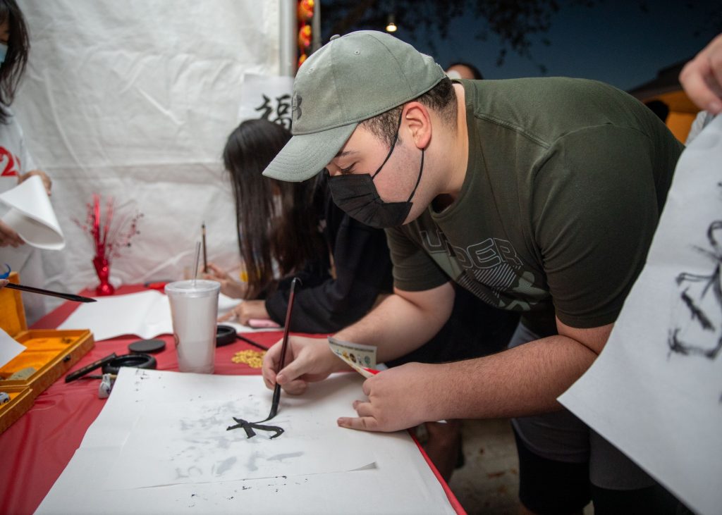 A student writes a character in the University of Miami Chinese Students and Scholars Association’s booth, as a part of the Lunar New Year Festival on the Lakeside Patio on Feb. 7, 2022.