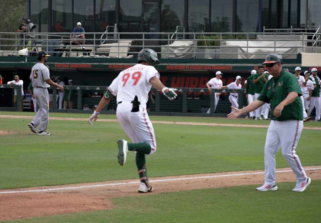 Freshman right fielder Lorenzo Carrier celebrates a second-inning grand slam with Miami head coach Gino DiMare in the Hurricanes' 11-1 win over Towson on Sunday, Feb. 20, 2022 at Mark Light Field