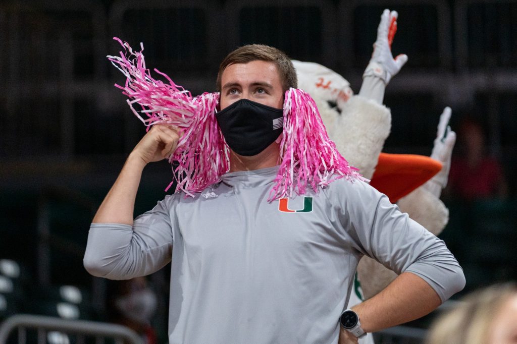A student fan flips his makeshift “hair”, fashioned out of two pink and white pom poms given out in honor of the day’s Breast Cancer Awareness game versus Florida State in The Watsco Center on Feb. 13, 2022.