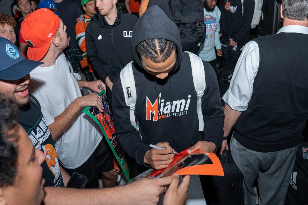 Third-year sophomore guard Isaiah Wong signs a fan’s poster after arriving back to the Watsco Center on March 27, 2022.