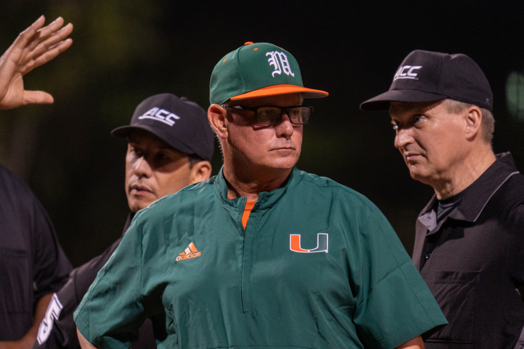 Head Coach Gino DiMare meets with umpires before the start of Miami's game versus Towson at Mark Light Field on February 18, 2022.