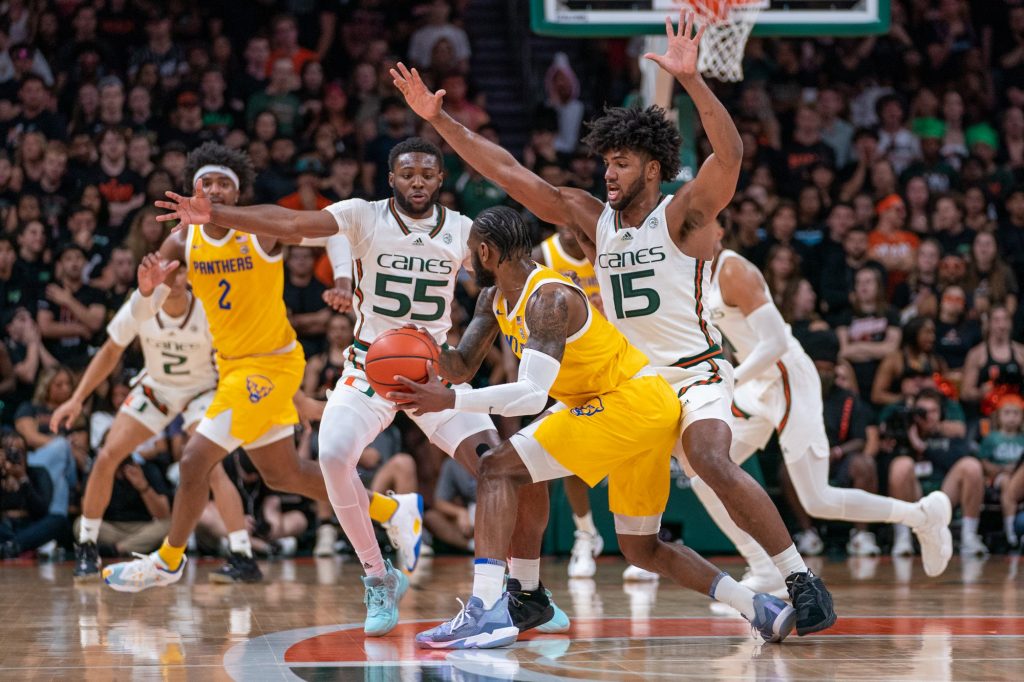 Sophomore guard Wooga Poplar and third-year sophomore forward Norchad Omier attempt to force a turnover during Miami's game versus the University of Pittsburgh in the Watsco Center on March 4, 2023.
