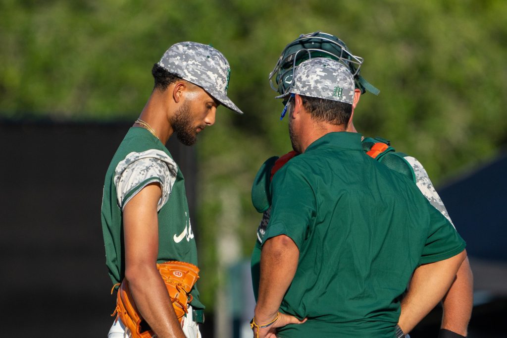 Junior right-handed pitcher Ronaldo Gallo speaks with his coach and catcher during a mound visit in the bottom of the third inning of Miami’s Coral Gables Regional game versus the University of Texas at Mark Light Field on June 4, 2023.